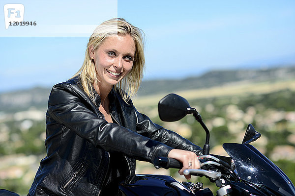 Porträt einer attraktiven jungen blonden Frau  die im Sommer mit dem Motorrad fährt.