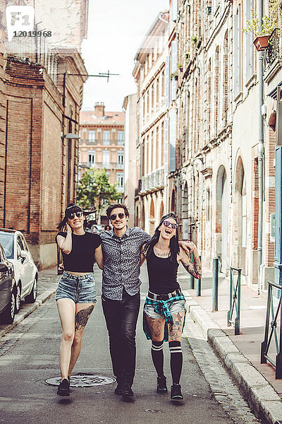 Drei junge Menschen gehen auf der Straße  Stadtbild