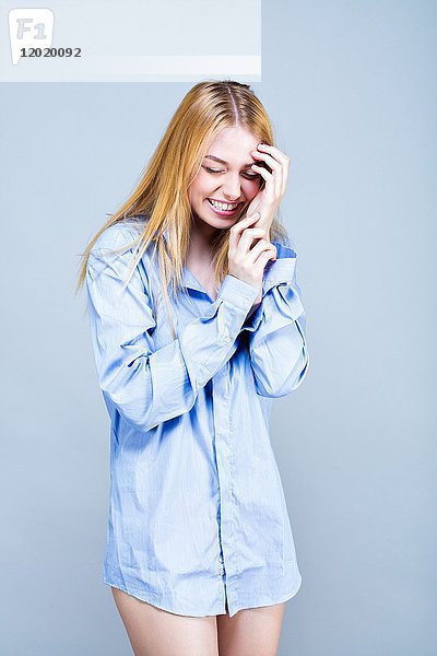 Porträt einer lächelnden jungen Frau im Hemd  eine Hand auf der Stirn  Augen geschlossene Mädchen