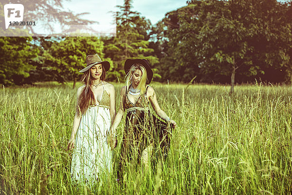 Porträt von zwei Mädchen  die sich auf einem Feld an den Händen halten