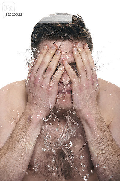 Oben-ohne-Mann  Wasser auf sein Gesicht spritzend  Gesicht in den Händen  Augen geschlossen