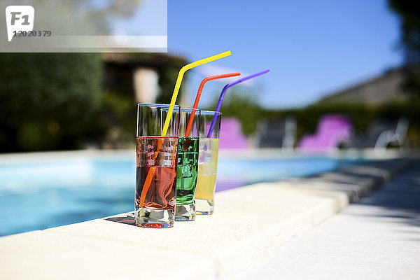 Drei tropische bunte Getränkecocktail mit Strohhalm auf der Poolside des Resort-Schwimmbades mit niemandem.