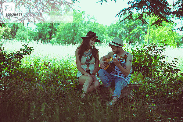 Porträt eines jungen Paares  sitzend  Hipster  Gitarre spielend