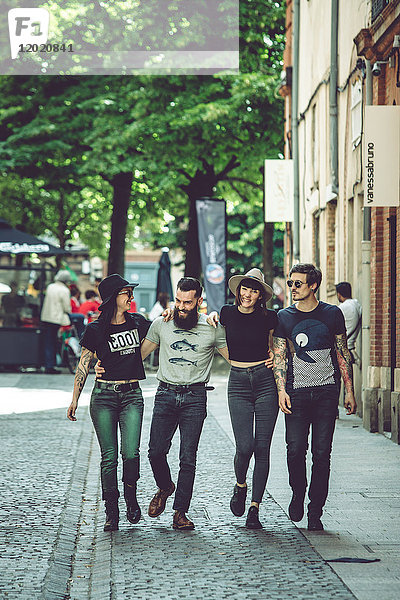 Gruppe junger Hipster  die eine Straße entlanggehen  städtische Umgebung