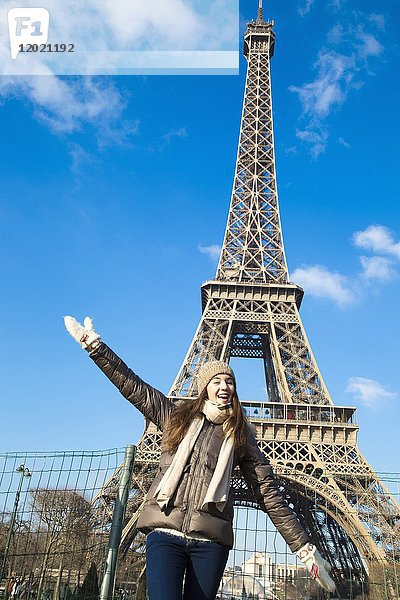 Fröhliches junges Mädchen posiert vor dem Eiffeil-Turm.