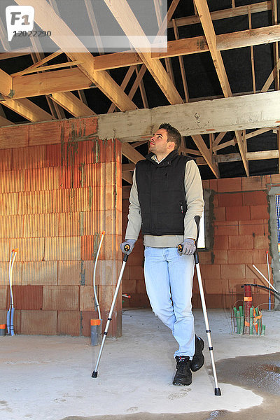 Frankreich  junger Arbeiter mit Krücken in einem Haus im Bau.