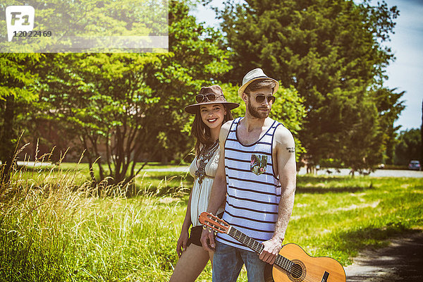 Porträt eines jungen Paares Hipsterfahrt auf dem Lande  eine Gitarre in der Hand