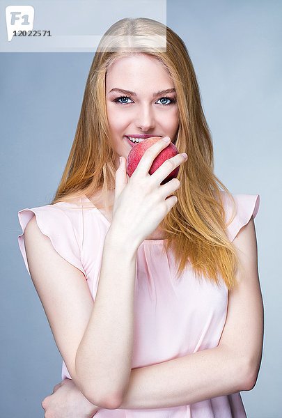 Porträt einer lächelnden jungen Frau  die sich den Mund füllt