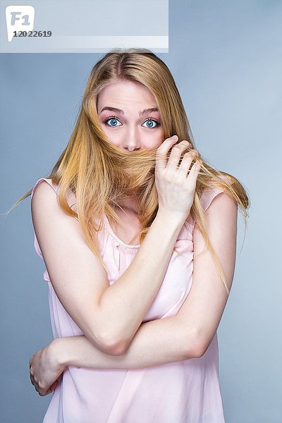 Porträt einer jungen staunenden Frau  Haare vor dem Mund