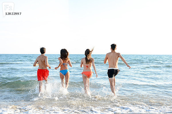 Frankreich  4 junge Leute laufen von hinten ins Meer  um zu baden.