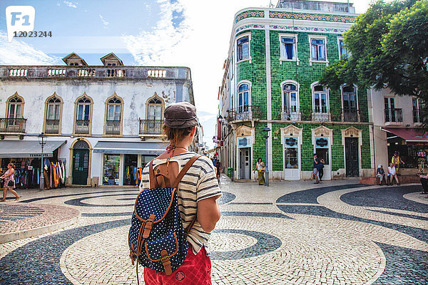 Junge Frau von hinten  beobachtet den Platz der Stadt Burgau  Region Algarve  Portugal