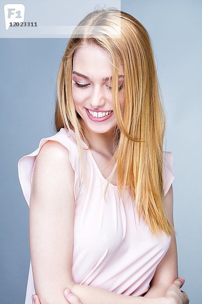 Porträt einer lächelnden jungen Frau mit gesenktem Kopf