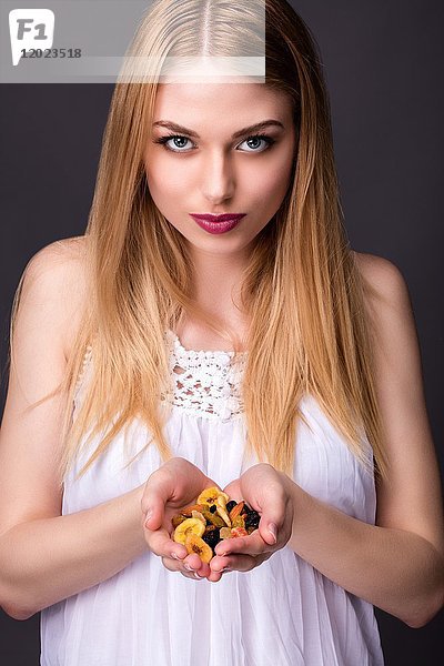 Porträt einer lächelnden jungen Frau  die Trockenfrüchte in den Händen hält