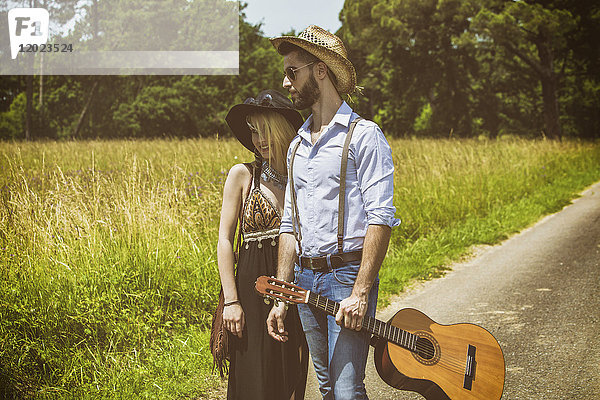 Porträt eines jungen Paares Hipsterfahrt auf dem Lande  eine Gitarre in der Hand