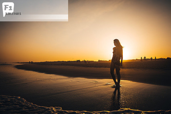 Junge Frau  die bei Sonnenuntergang am Strand Praia do Barril spazieren geht  Stadt deTavira  Region Algarve  Portugal