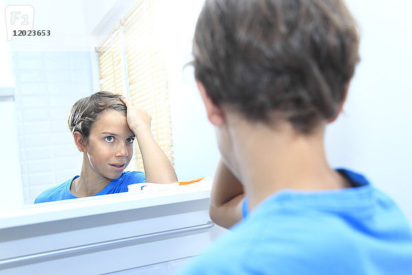 Frankreich  ein Junge im Badezimmer  der seine Haare im Spiegel betrachtet.