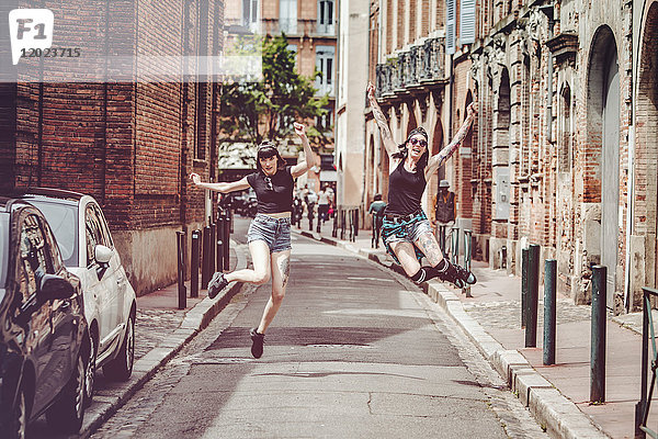Freudensprung von zwei jungen Frauen auf einer Straße im Stadtzentrum