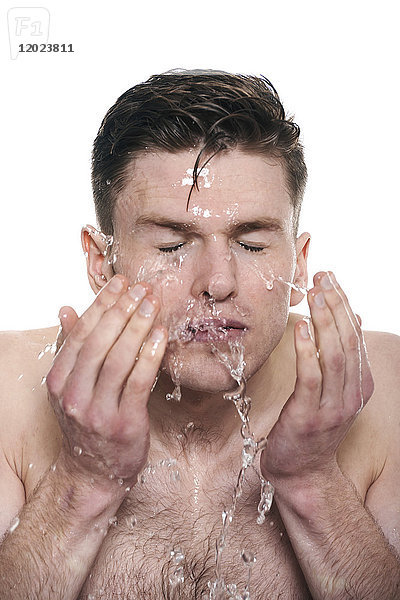 Oben-ohne-Mann  Wasser auf sein Gesicht spritzend  Augen geschlossen