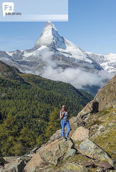 Wanderer steht auf Felsen  im Rücken das schneebedeckte Matterhorn  Wallis  Schweiz  Europa