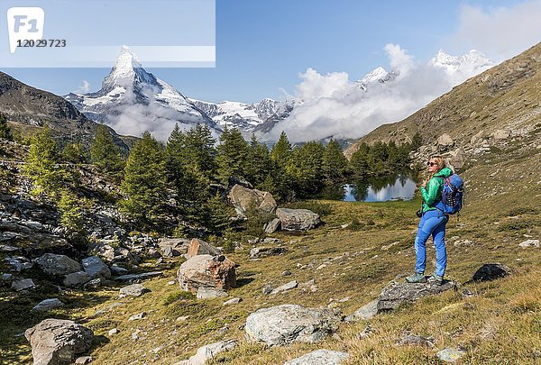 Wanderer steht auf Felsen und schaut in die Ferne  hinter dem Grindijsee und dem schneebedeckten Matterhorn  Wallis  Schweiz  Europa