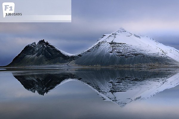 Vulkanische Berge im Winter mit Spiegelung im Wasser  in der Nähe von Djupivogur  East Island  Island