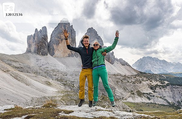 Zwei Wanderer machen einen Luftsprung  Nordwände der Drei Zinnen  Sextner Dolomiten  Südtirol  Trentino-Südtirol  Südtirol  Italien  Europa