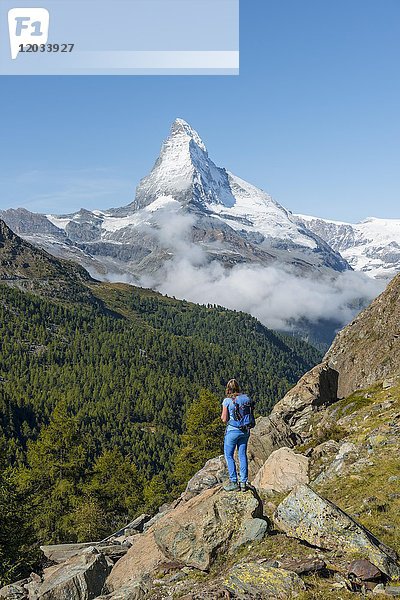 Wanderer steht auf einem Felsen und schaut in die Ferne  auf das hintere schneebedeckte Matterhorn  Wallis  Schweiz  Europa