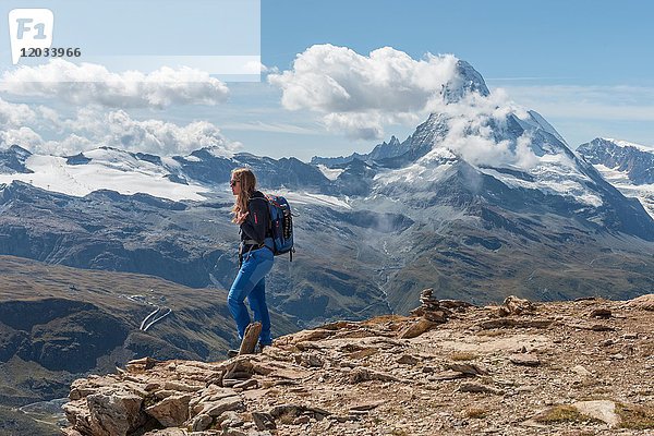 Wanderer steht auf Felsen  im Rücken das schneebedeckte Matterhorn  Wallis  Schweiz  Europa