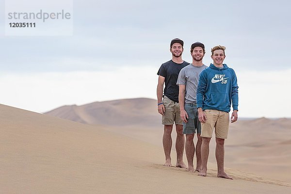 Drei junge Männer auf einer Sanddüne  Namib-Wüste  Namibia  Afrika