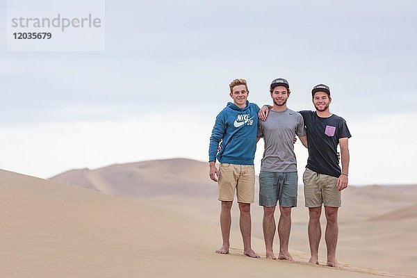 Drei junge Männer auf einer Sanddüne  Namib-Wüste  Namibia  Afrika