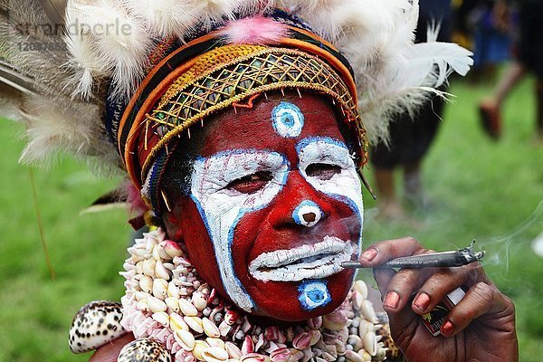 Ureinwohner  Portrait  bemalt mit Kopfschmuck  rauchend  Hochland-Stamm War Kang  Sing-Sing Festival  Goroka  Papua-Neuguinea  Ozeanien