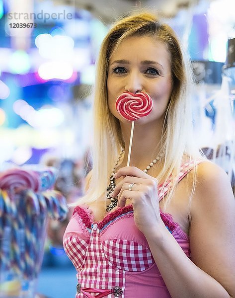 Blonde Frau im rosa Dirndl mit Lolli in Herzform  Oktoberfest  München  Oberbayern  Bayern  Deutschland  Europa