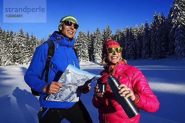 Zwei Wanderer auf Premium-Winterwanderweg  machen Rast  Hemmersuppenalm  Reit im Winkl  Chiemgau  Oberbayern  Bayern  Deutschland  Europa