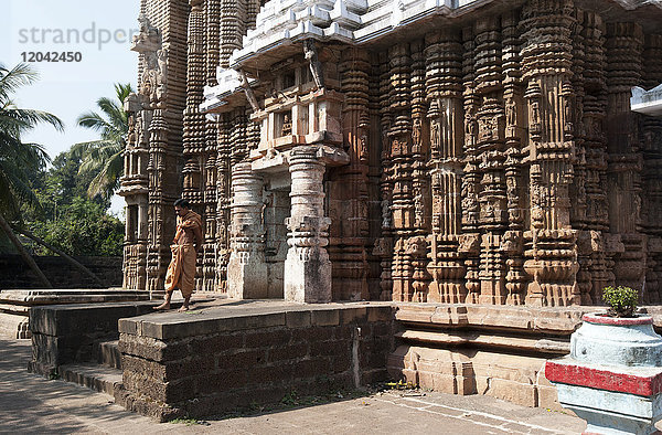 Hindupriester in safranfarbenen Gewändern vor dem kunstvoll geschnitzten Madhava-Tempel aus dem 13. Jahrhundert  der Lord Vishnu gewidmet ist  Madhava  Odisha  Indien  Asien