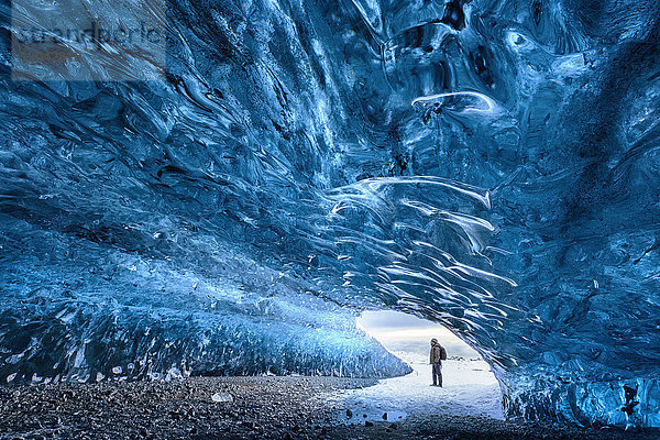 Blick aus einer Eishöhle unter dem Vatnajokull-Gletscher mit einer Person als Maßstab  in der Nähe der Jokulsarlon-Lagune  Südisland  Polarregionen