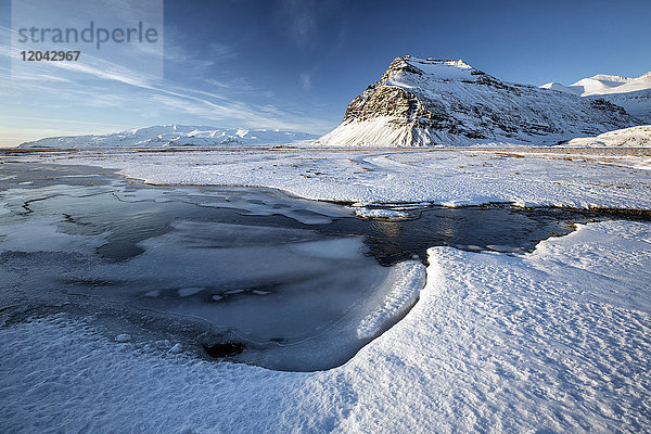 Schneebedeckte Winterlandschaft mit gefrorenem Teich  Berg und Vatnajokull-Gletscher  in der Nähe der Lagune Jokulsarlon  Südisland  Polarregionen