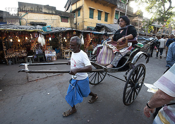 Rikscha-Wallah im alten Stil  der eine Frau und ihre Einkäufe durch die Straßen von Kolkata vor dem Kali-Tempel zieht  Kolkata (Kalkutta)  Westbengalen  Indien  Asien