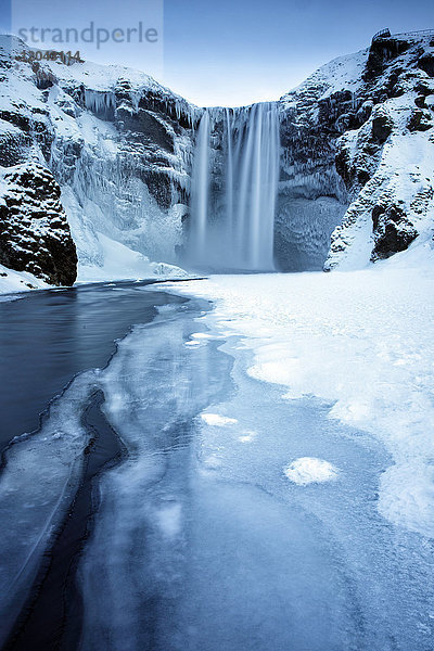 Winteransicht des Skogafoss-Wasserfalls  mit eiszapfenbedeckten Felsen und verschneitem Vorgelände  Skogar  Südisland  Polarregionen