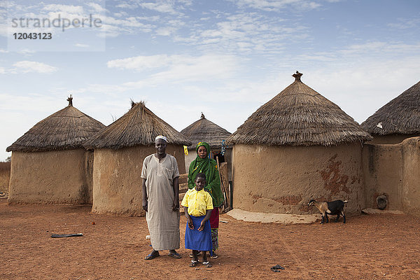 Ein junges Schulmädchen mit ihren Eltern vor deren Haus in Tinguri  Nordghana  Westafrika  Afrika