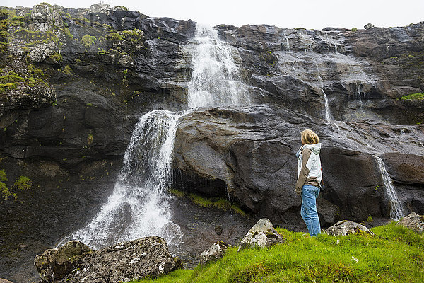 Frau mit Blick auf einen Wasserfall in Estuyroy  Färöer Inseln  Dänemark