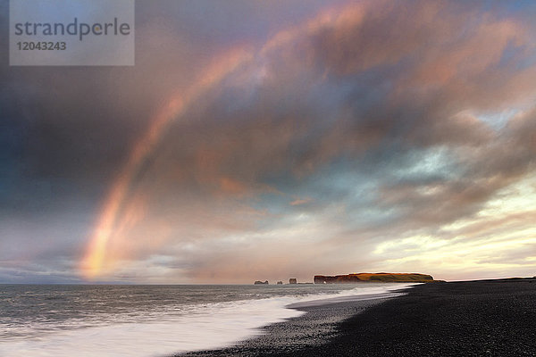 Fernsicht auf Dyrholaey bei Sonnenaufgang mit Regenbogen  vom Strand von Halsanefs Hellir bei Vik  Südisland  Polarregionen