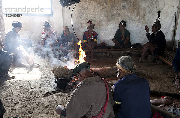 Naga-Männer sitzen plaudernd um das zentrale Feuer in ihrem Dorf Murung (Dorfhalle)  Dorf Hongphui  Nagaland  Indien  Asien