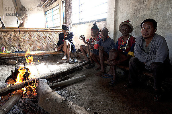 Naga-Männer sitzen plaudernd am Feuer im Dorf Muting (Versammlungsraum)  Nagaland  Indien  Asien