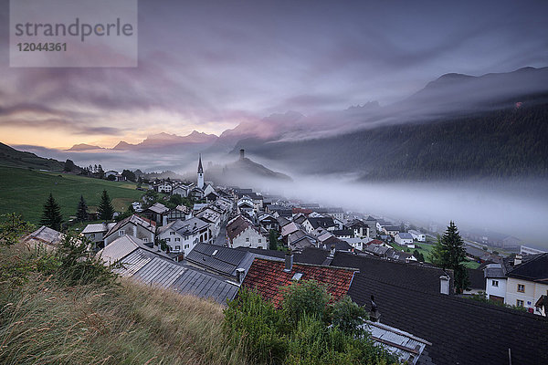 Rosa Wolken und Nebel über dem Dorf Ardez in der Morgendämmerung  Bezirk Inn  Unterengadin  Kanton Graubünden  Schweiz  Europa