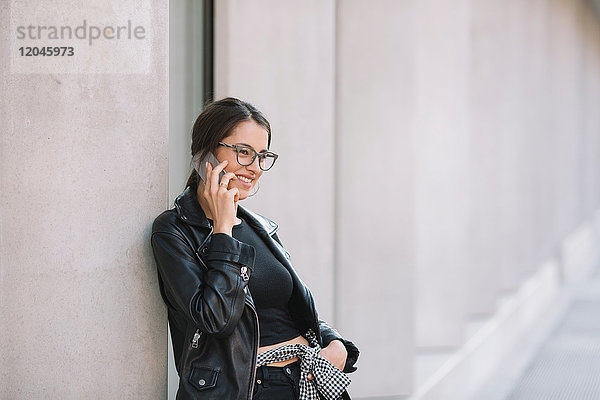 An die Wand gelehnte Frau mit Smartphone