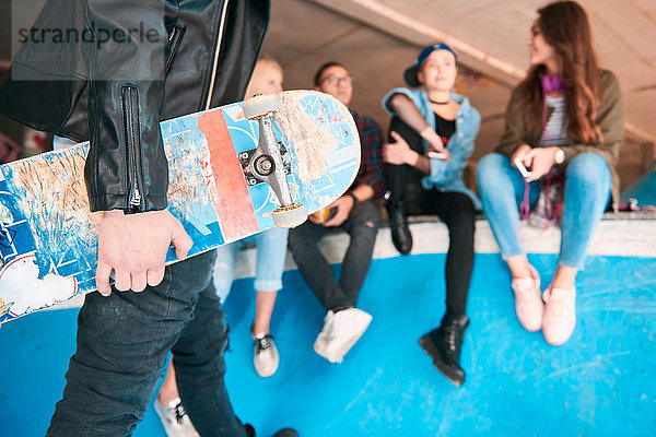 Schnappschuss eines jungen männlichen Skateboardfahrers  der ein Skateboard auf der Rampe trägt