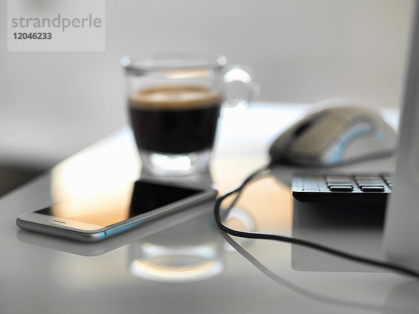 Morgenkaffee am Büroschreibtisch mit Mobiltelefon und Computer