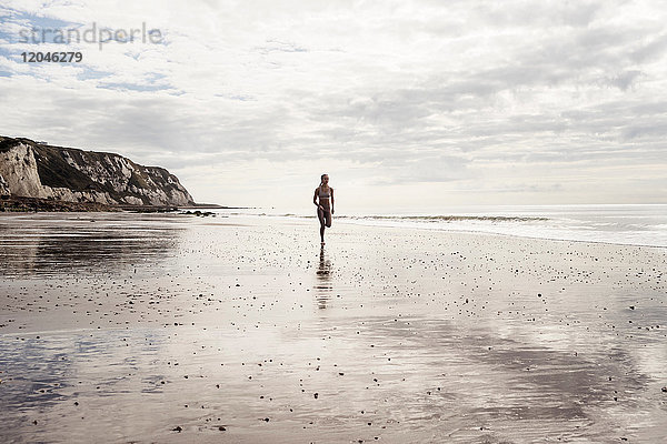 Junge Frau rennt am Strand entlang