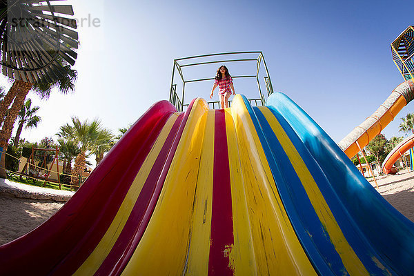 Niedrigwinkel-Ansicht eines Mädchens  das sich darauf vorbereitet  auf einer Spielparkrutsche zu rutschen