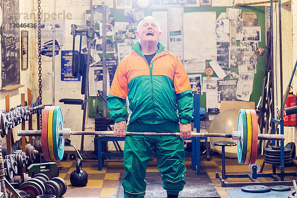 Älterer männlicher Powerlifter kämpft im Fitnessstudio mit dem Heben von Langhantel